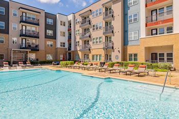A large swimming pool in front of apartment buildings.